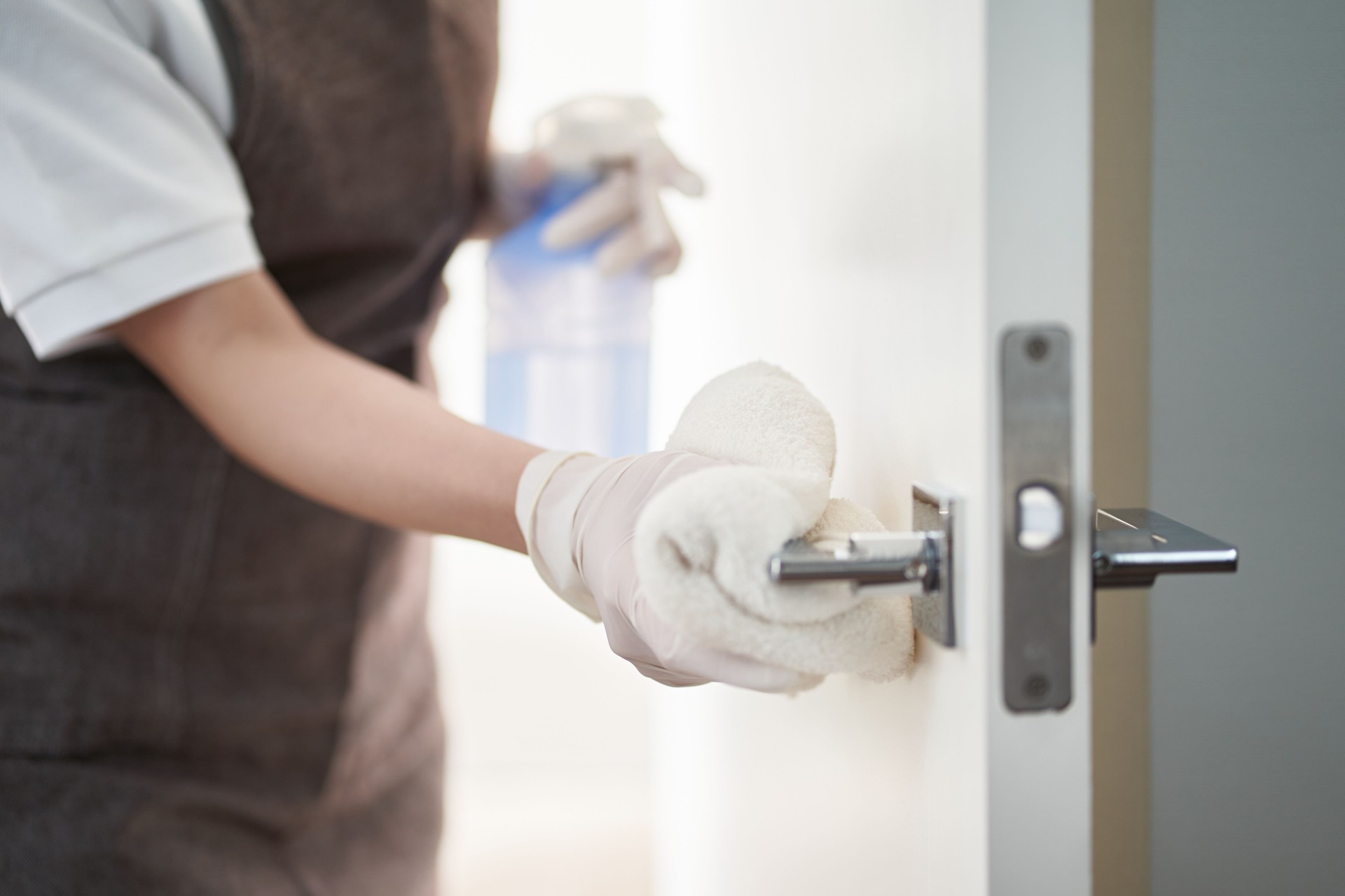 Asian woman sterilizing door handles with alcohol
